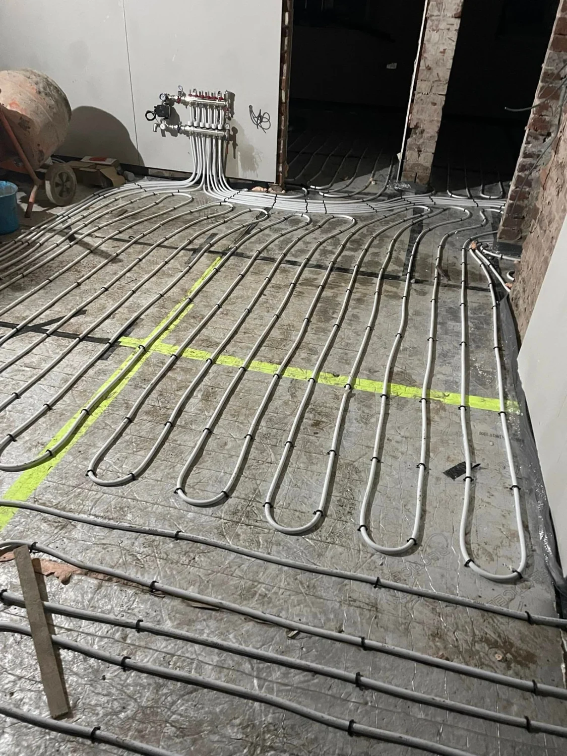 Underfloor heating pipework laid across a floor and connected to a manifold